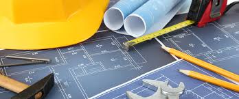 Engineering tools and blueprints with hard hat, tape measure, and drafting instruments